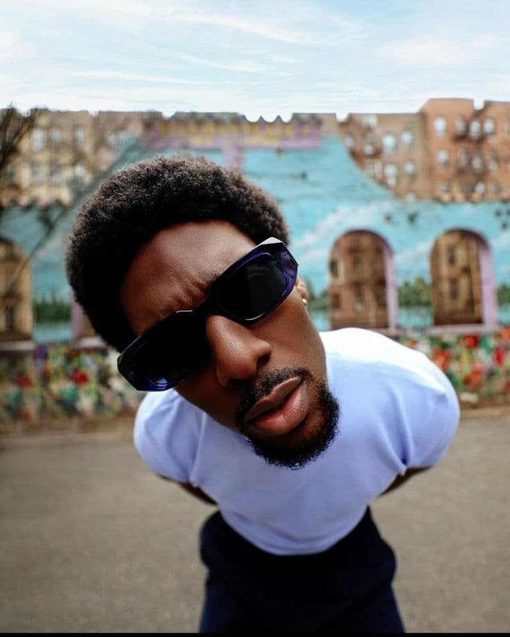 Street portrait of a man in sunglasses against a brightly painted mural